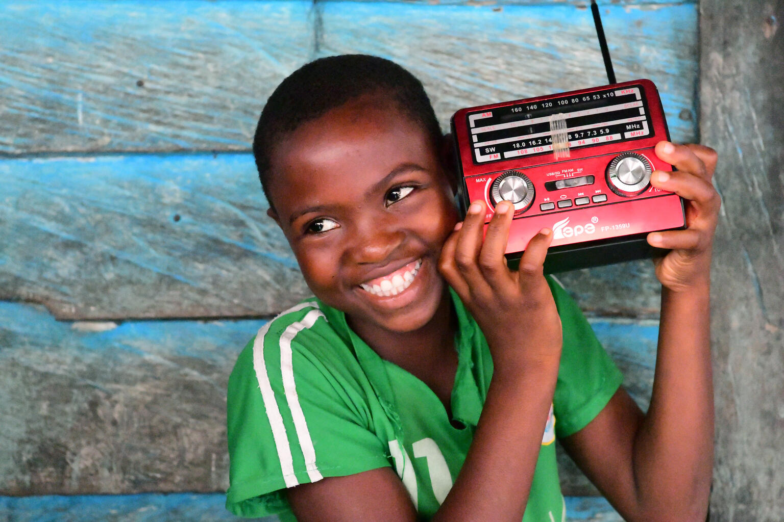 Un niño sonríe mientras escucha un transistor