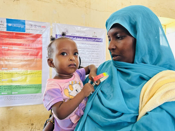 Una niña y su madre en una clínica móvil de UNICEF en Sudán.
