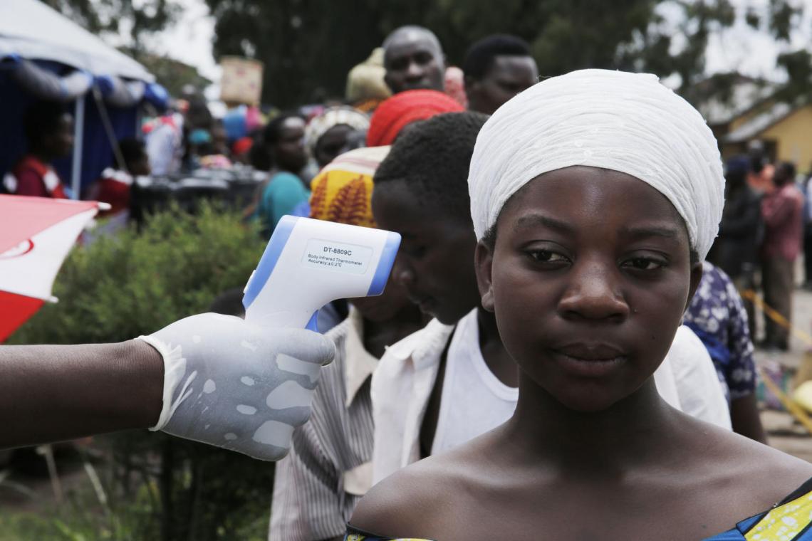 Uganda, 2019. Un trabajador de la salud toma la temperatura de las personas alineadas en un centro de detección en la frontera con la República Democrática del Congo.