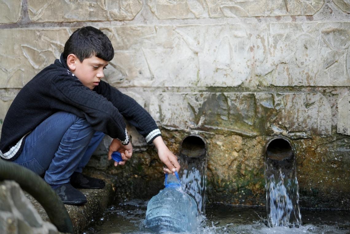Un niño recoge agua potable en una aldea de Líbano