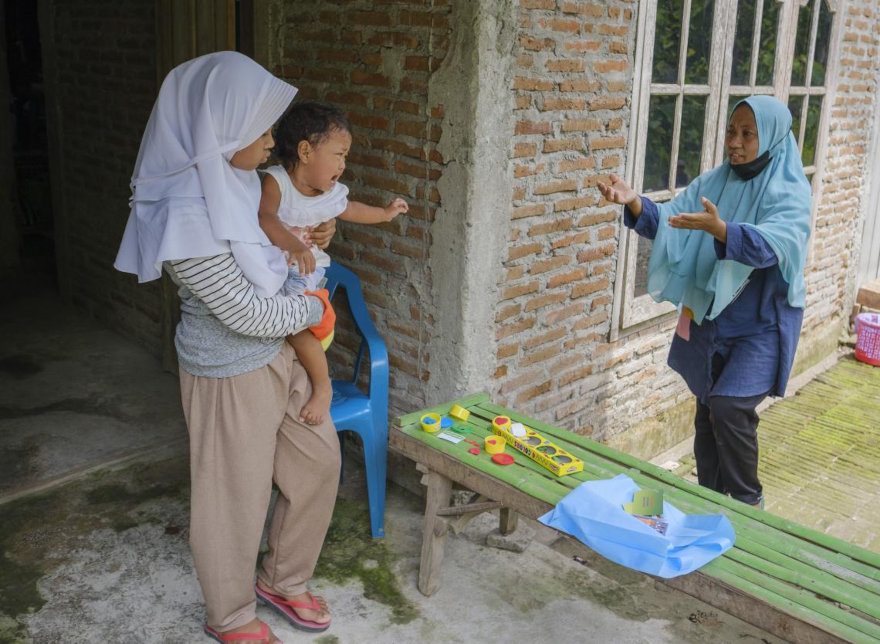 Ayra cuida a su hermana mientras su madre trabaja, Indonesia.