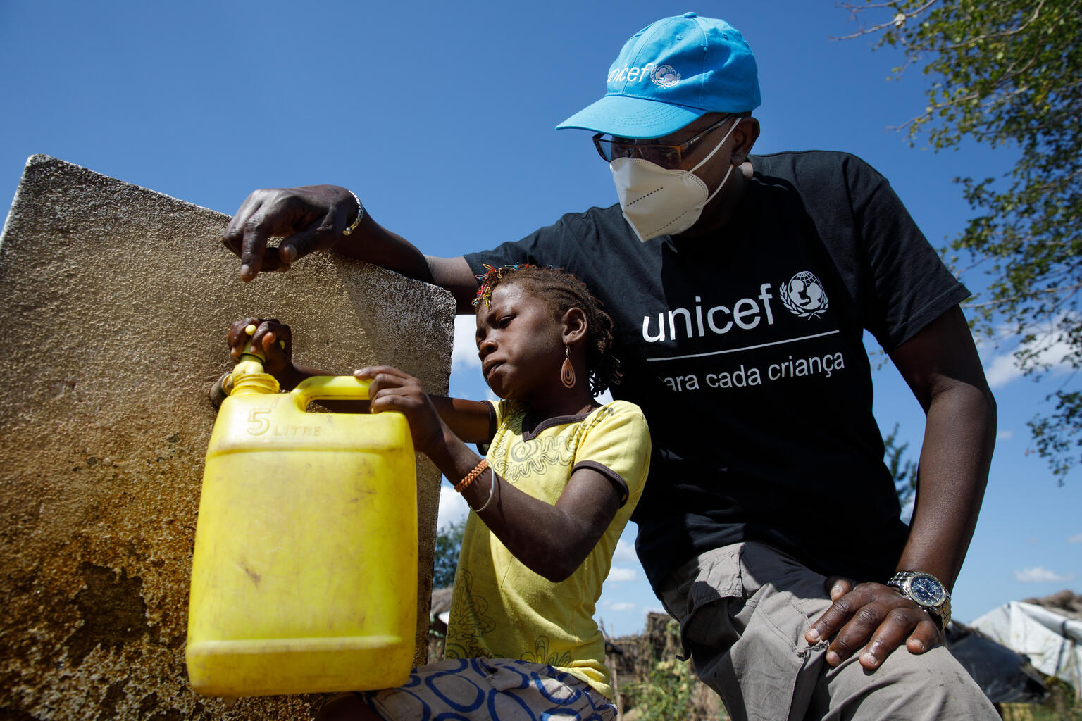 Un responsable de UNICEF y una niña recogen agua potable en Mozambique