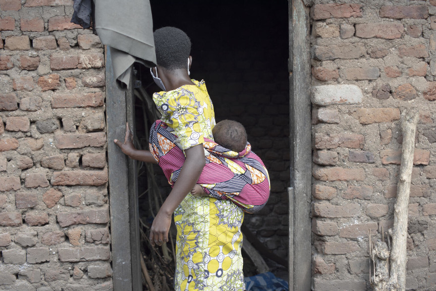 Una niña de 14 años, madre adolescente, transporta su bebé en Uganda.
