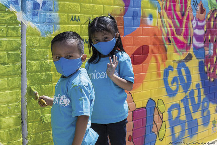 Un niño y una niña pintan un mural en el patio de su escuela