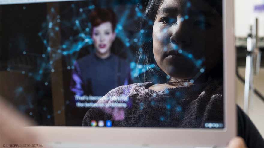 Un ordenador portátil refleja el rostro de una niña mientras mira un video de Internet