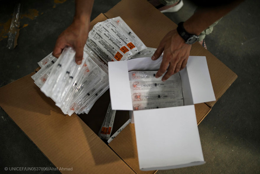 Personal de UNICEF revisa una caja de jeringuillas en un almacén de India