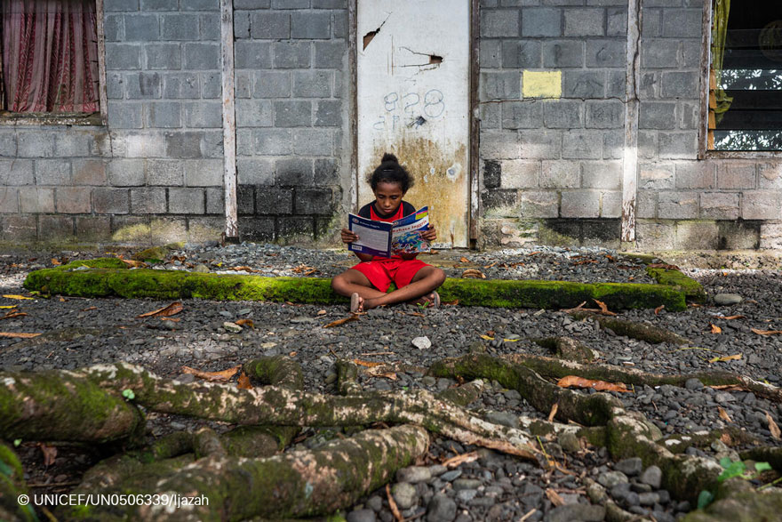 Una niña lee a las puertas de su casa en Indonesia
