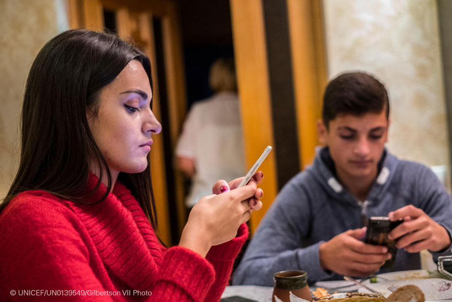 Dos adolescentes utilizan su teléfono móvil durante la comida