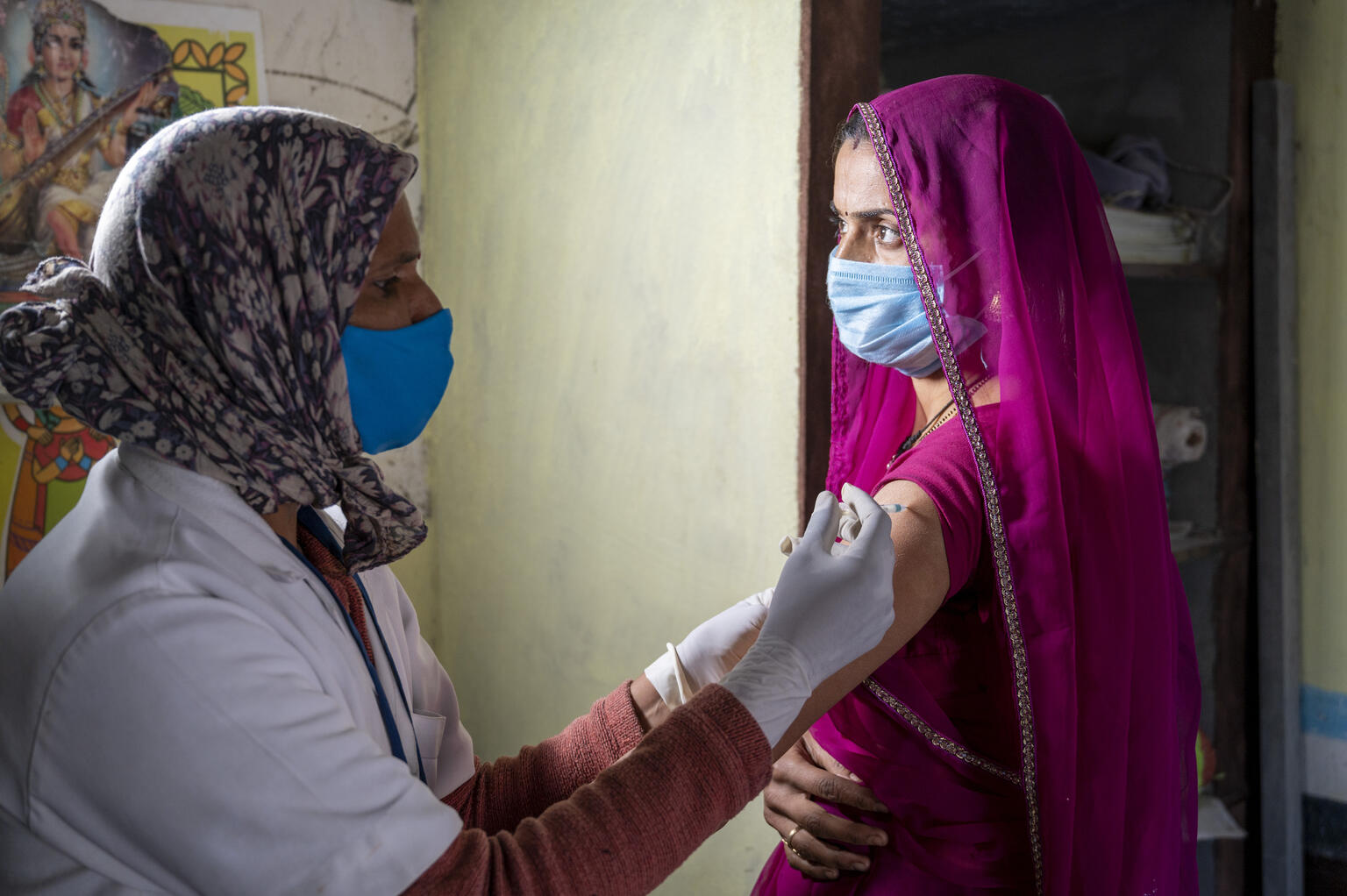 Una mujer de Bangladesh con mascarilla recibe una vacuna 