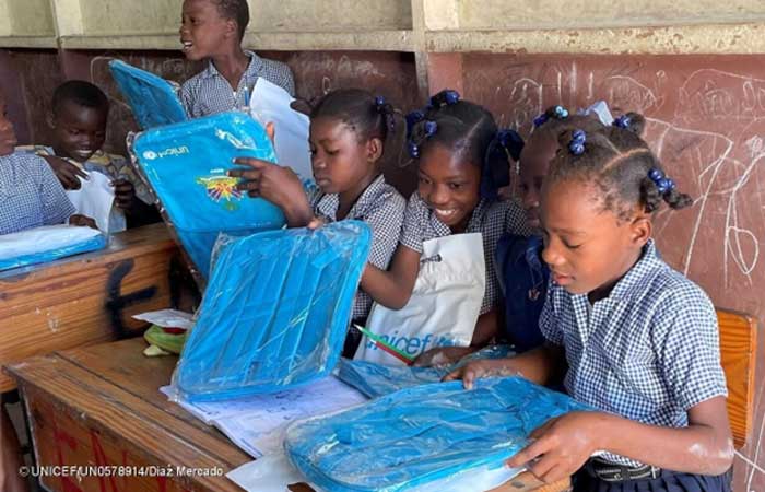 Unas niñas de Haití abren ilusionadas sus libros escolares de UNICEF en la escuela