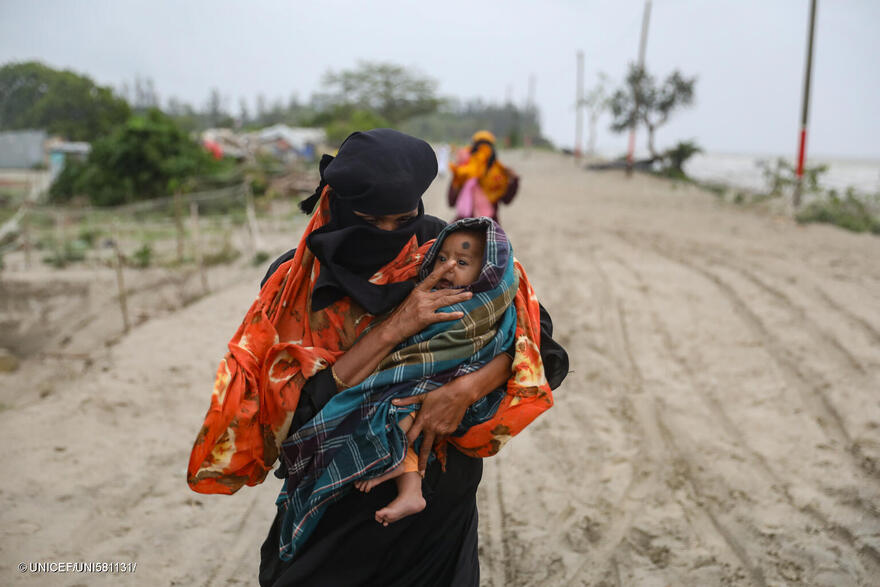Habitantes de la aldea de Panjupara caminan hacia el refugio con sus hijos y valiosos enseres domésticos durante las lluvias en Kuakata, en previsión de que el ciclón Remal toque tierra en Bangladesh el 26 de mayo de 2024.