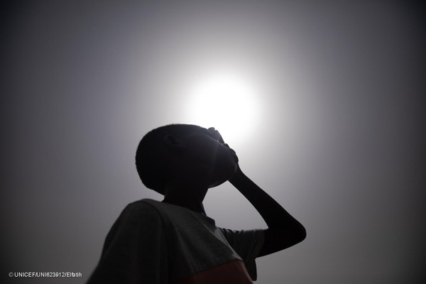 Un niño de Sudán se tapa los ojos para protegerse del sol