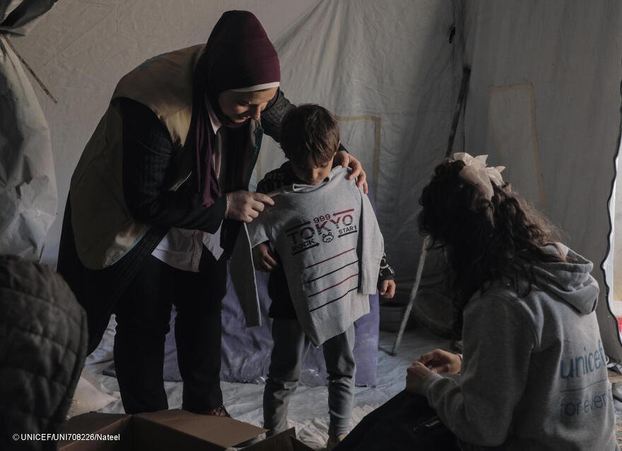 Personal humanitario entregando prendas de abrigo a niños desplazados en Gaza