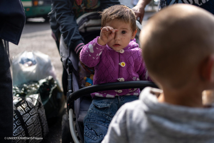 Faina, un bebé de un año, está sentada en un cochecito en la parada de autobús del pueblo de Dachne, en Ucrania, esperando un autobús para evacuar la zona y huir de los bombardeos..