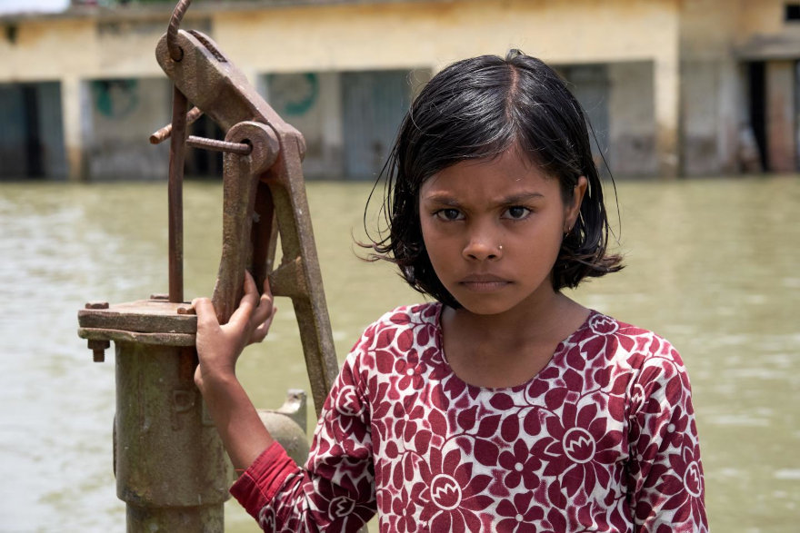 Una niña de Bangladesh delante de la única fuente de agua limpia de su entorno escolar.