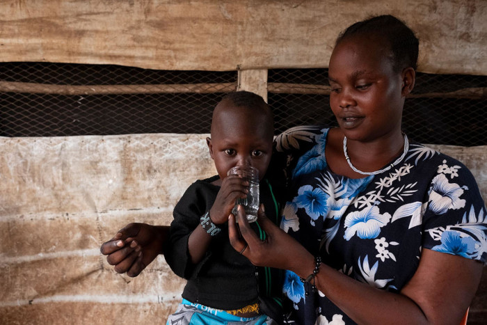 Una madre da agua potable a su niño.