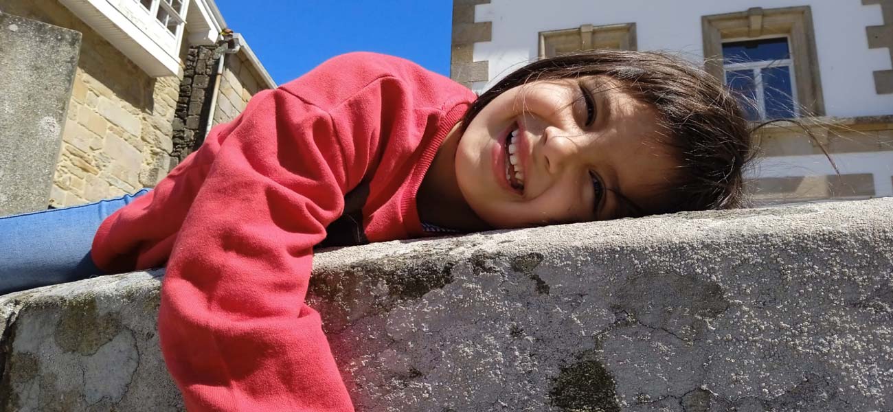Una niña sonríe y juega en las calles de una localidad Gallega