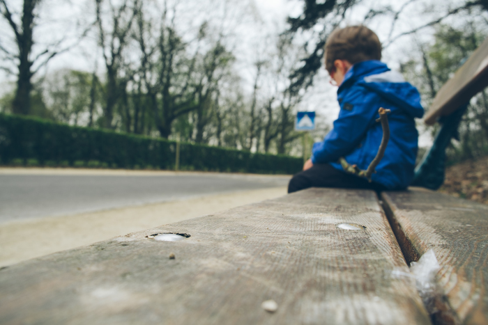 Un niño sentado en un banco.