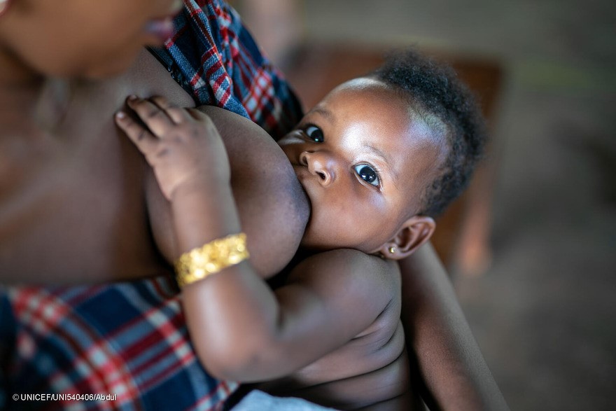 El 13 de marzo de 2024 en Jinja, Uganda, una madre amamanta a su bebé mientras esperan su turno para la vacunación en la clínica para niños pequeños del hospital de referencia de Jinja.