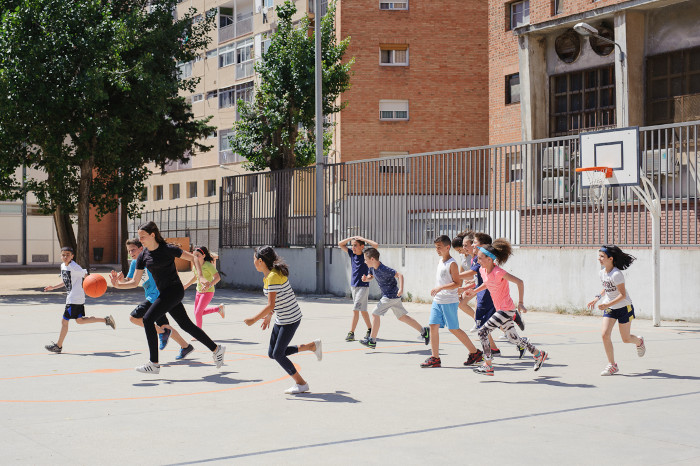 Niños y niñas jugando al baloncesto.