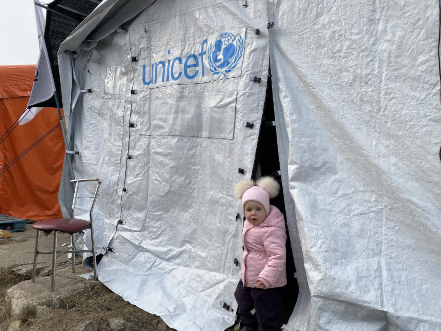Una niña se asoma de una tienda de campaña de UNICEF en Polonia.