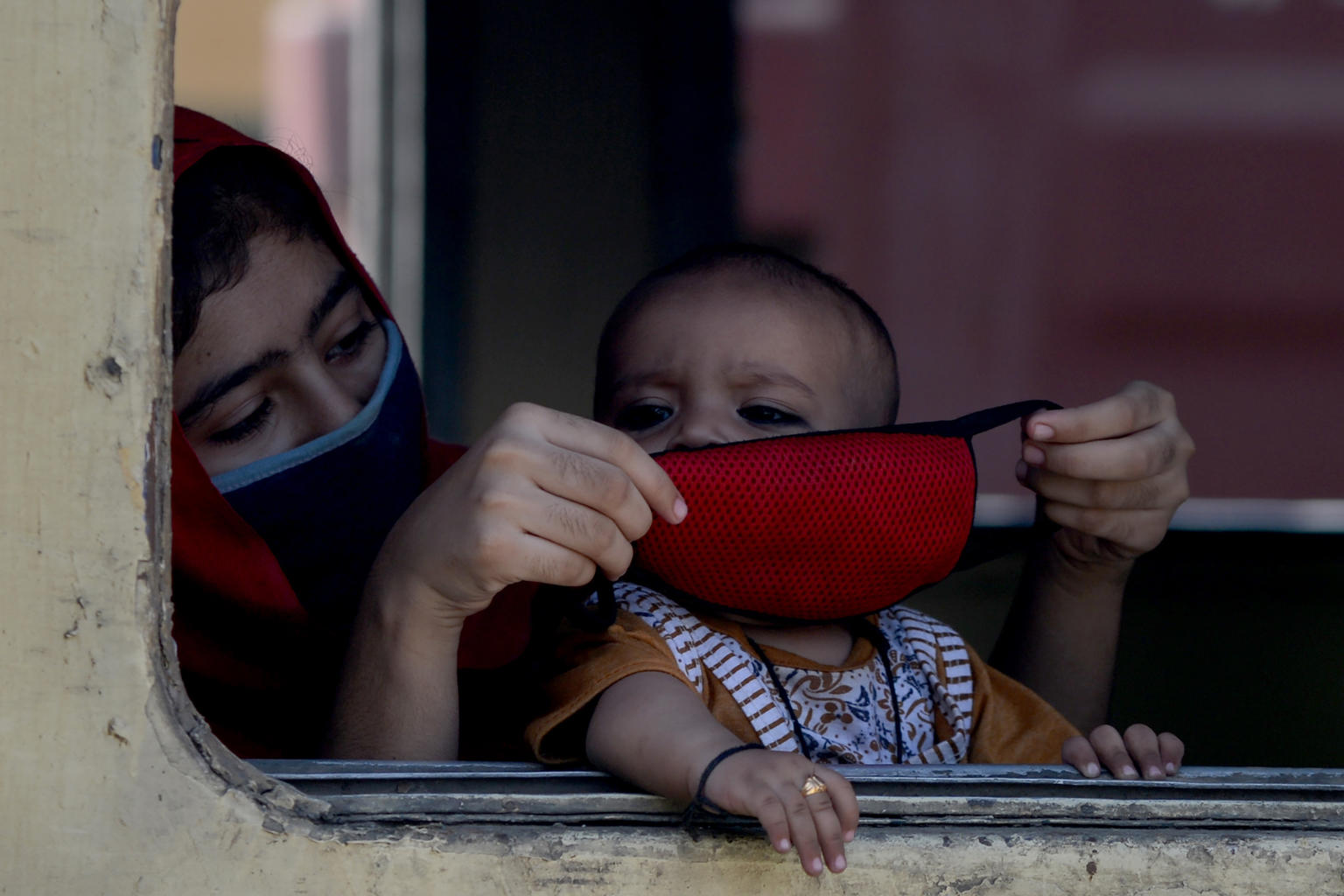 Una madre le coloca la mascarilla a su bebé en un tren en India