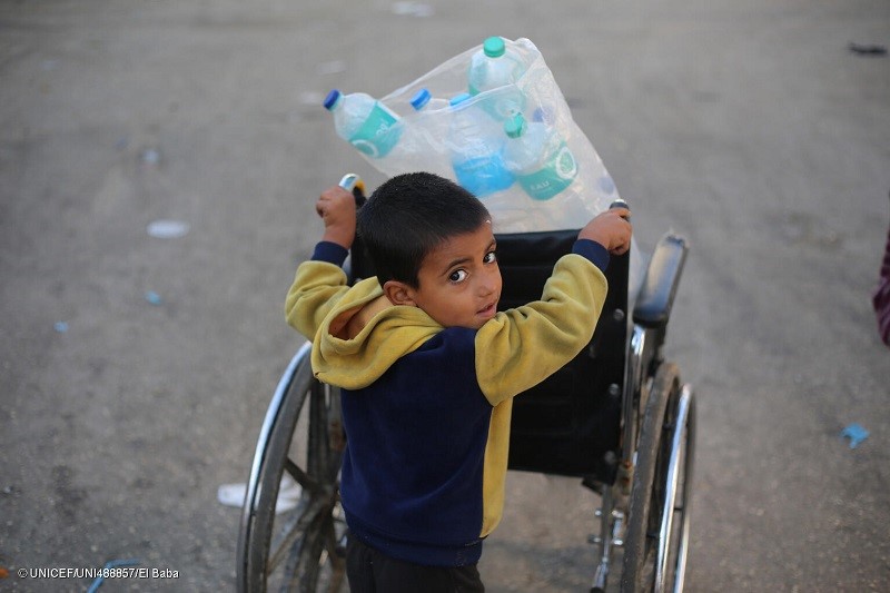 Un niño carga varias botellas de agua vacías en la Franja de Gaza