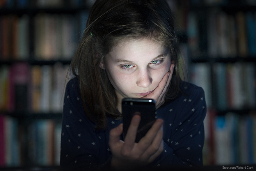 Una niña mira la pantalla de un móvil con gesto serio