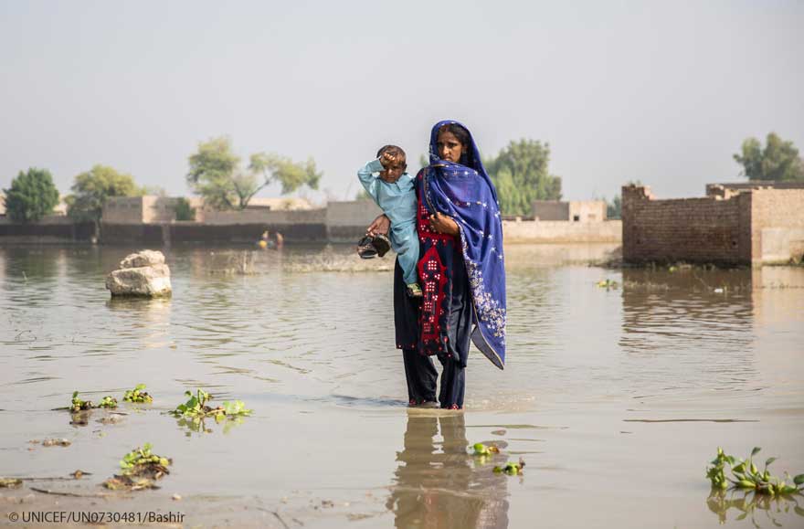 Una mujer lleva en brazos a su hijo en medio de las inundaciones que asolan Pakistán