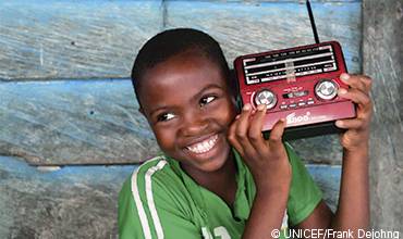 Un niño sonríe mientras escucha un transistor