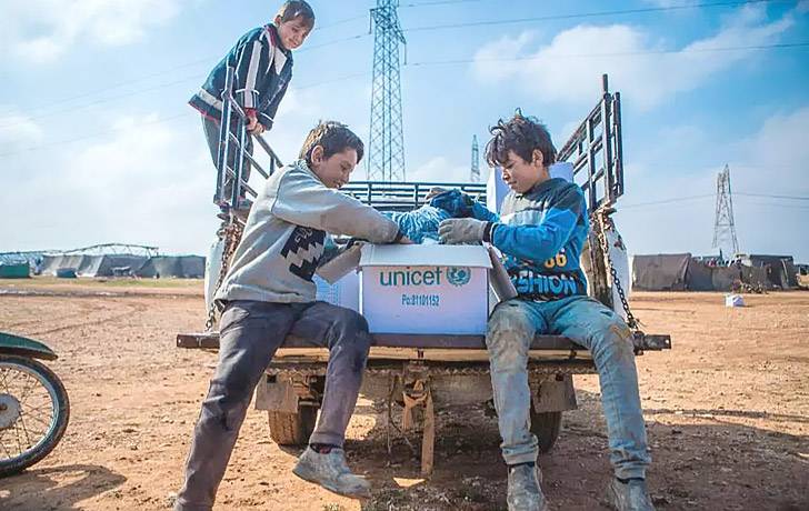 Emergencia y ayuda humanitaria Niños abriendo una caja de suministros UNICEF