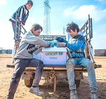 Emergencia y ayuda humanitaria Niños abriendo una caja suministros UNICEF