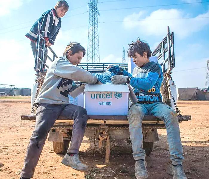 Emergencia y ayuda humanitaria Niños abriendo una caja de suministros UNICEF