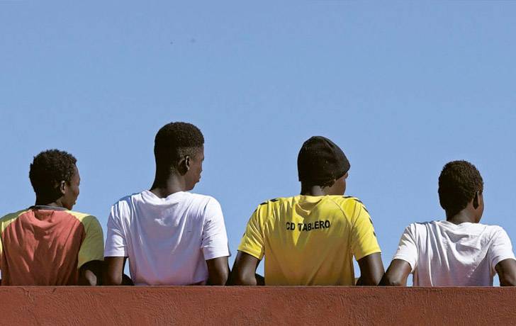 Niños migrantes no acompañados Varios niños adolescentes de espala mirando al horizonte