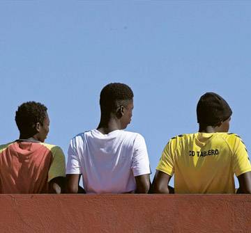Niños migrantes no acompañados Un grupo de niños adolescentes de espaldas mirando hacia el horizonte