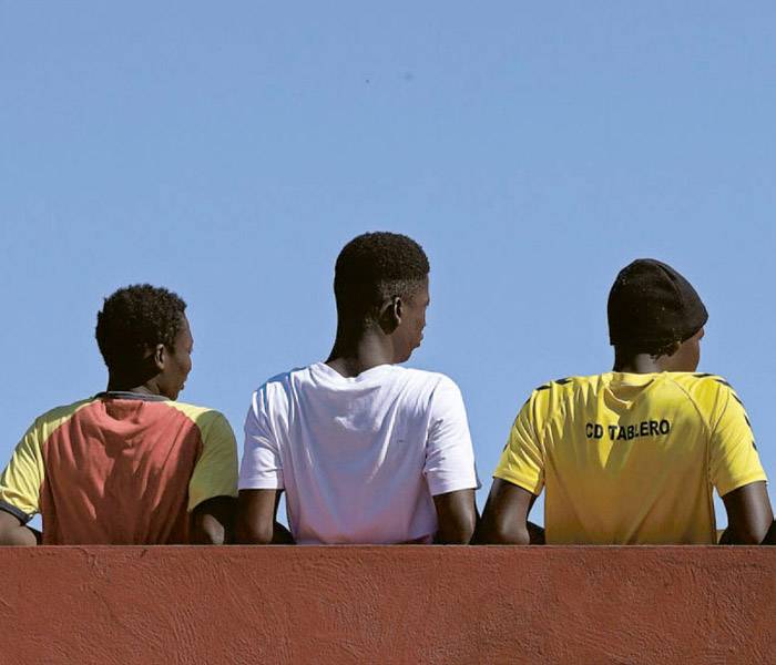 Niños migrantes no acompañados Un grupo de adolescentes de espaldas mirando hacia el horizonte