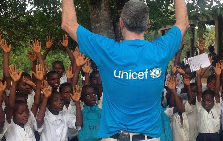 Juanma Iturriaga de espaldas con camiseta de UNICEF y rodeado de niños