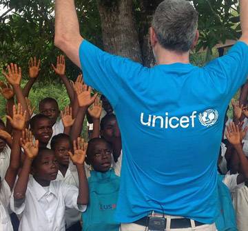  Juanma Iturriaga de espaldas con camiseta de UNICEF y rodeado de niños