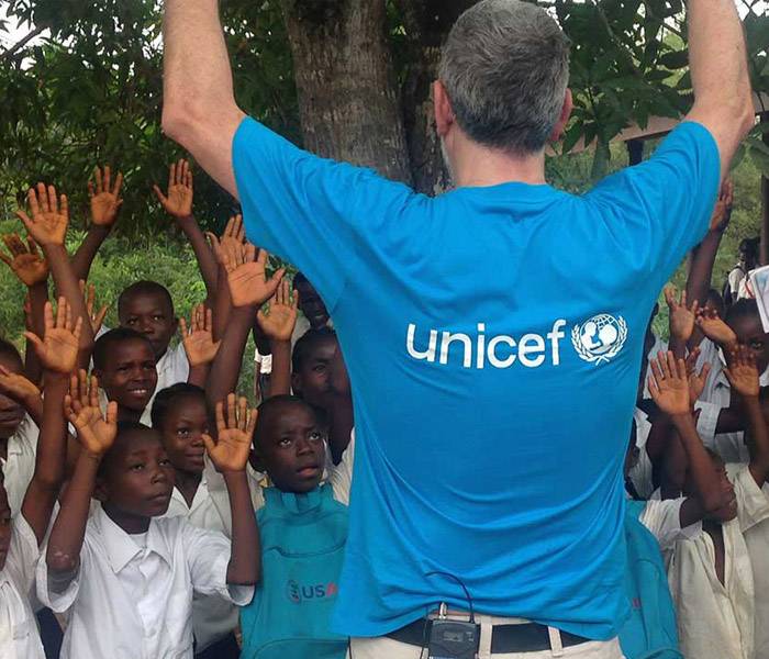  Juanma Iturriaga de espaldas con camiseta de UNICEF y rodeado de niños
