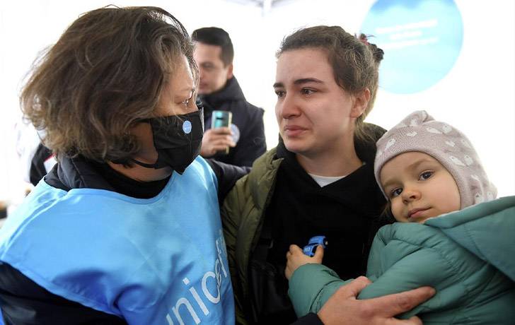Conflicto en Ucrania: 7,3 millones de niños y niñas de Ucrania necesitan ayuda urgente. Una persona de los cascos azules ayudando a una mujer y su cría en brazos