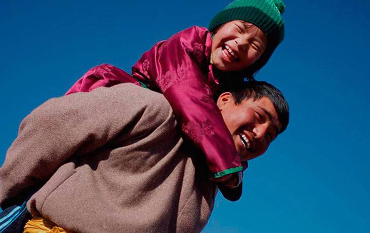 Seguros de vida - UNICEF Un adulto llevando a caballito a un niño sobre su espalda y ambos sonriendo