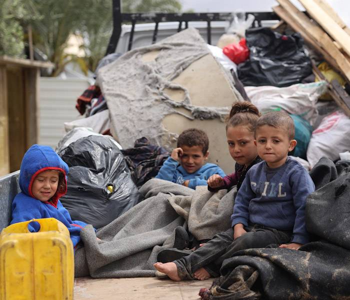 Niños durante su desplazamiento en Rafah Niños sentados en la parte trasera de un camión