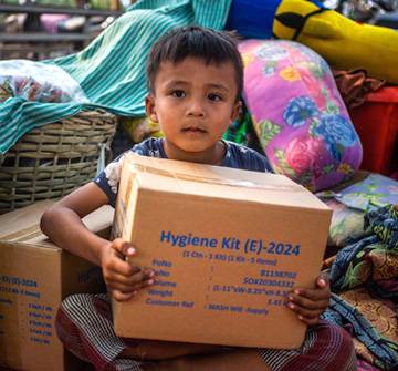 El 28 de marzo de 2025, un poderoso terremoto de magnitud 7,7 golpeó Mandalay, Myanmar. Phone Payae, de 5 años, posa para una fotografía sosteniendo una caja de suministros WASH de UNICEF