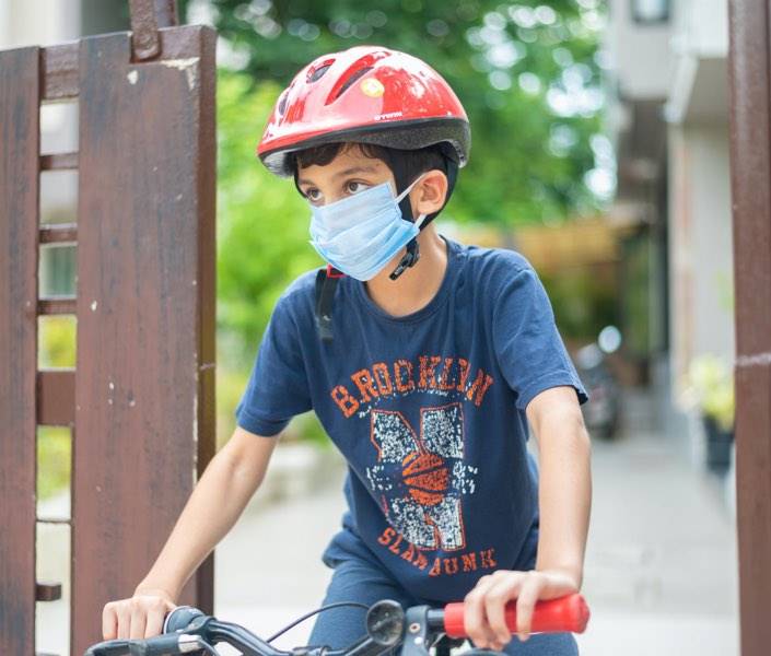 Imagen de un niño con mascarilla montado en una bicicleta